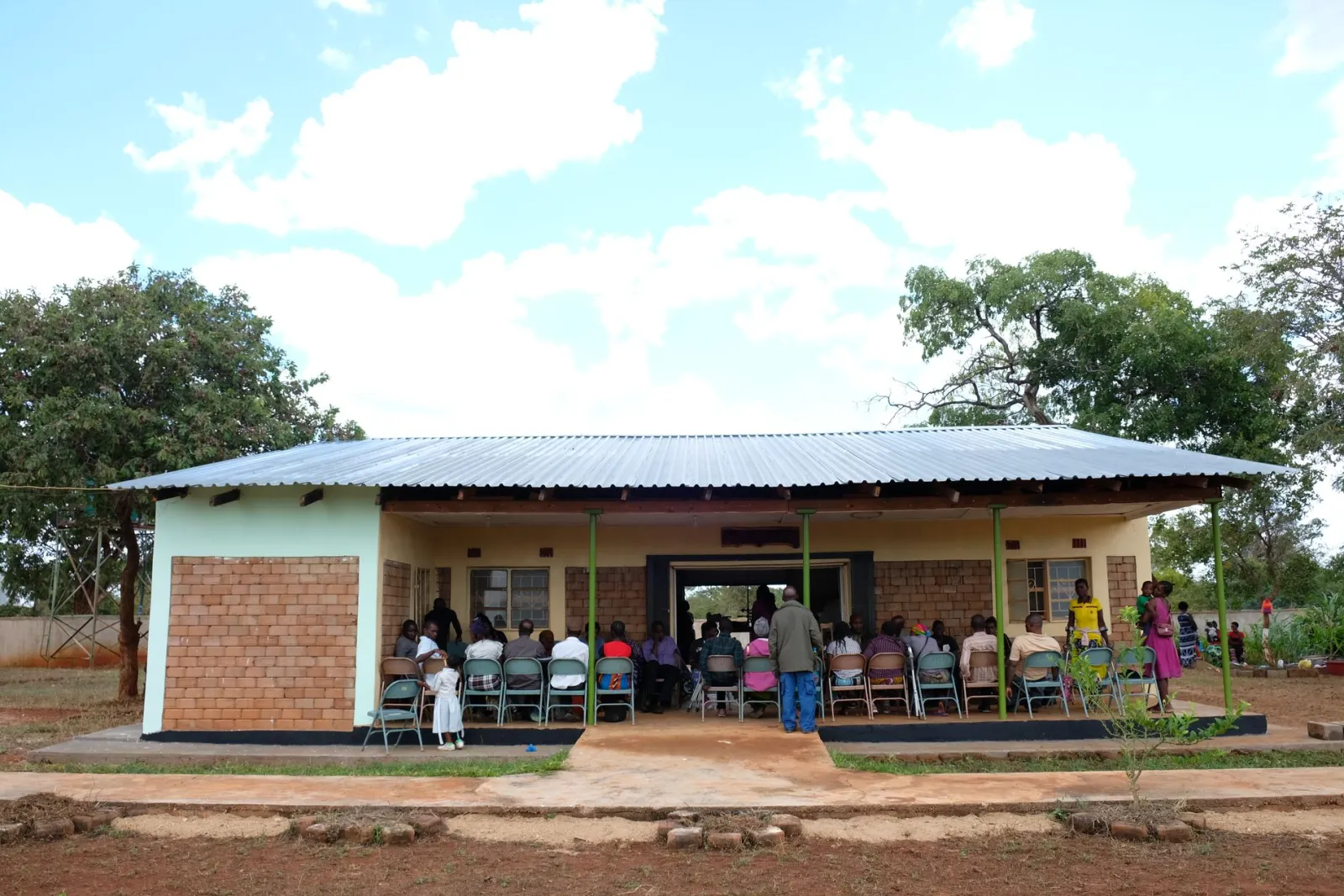 Patients sitting together in front of the clinic. Patients are transported to the clinic by bus at the start of the 10-day visit. Some receive help straight away, while others require more extensive work. The following six days are spent making and repairing devices, before patients return in the final days for fittings and adjustments.